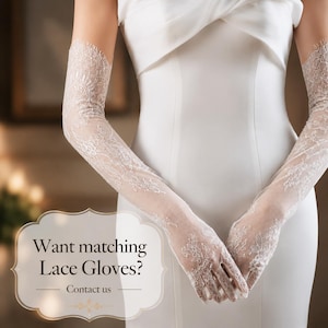 Puede incluir: Un par de guantes largos de encaje blanco con intrincados patrones florales y bordes festoneados, que se extienden m&aacute;s all&aacute; de los codos. Una superposici&oacute;n decorativa a la izquierda muestra el texto: Want matching Lace Gloves? Contact us.
