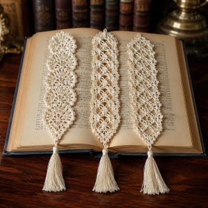 May include: Three off-white crochet bookmarks featuring intricate lace patterns and delicate thread work. Each bookmark is finished with a matching tassel at the bottom, showcasing detailed needlework and a long, slender rectangular shape.