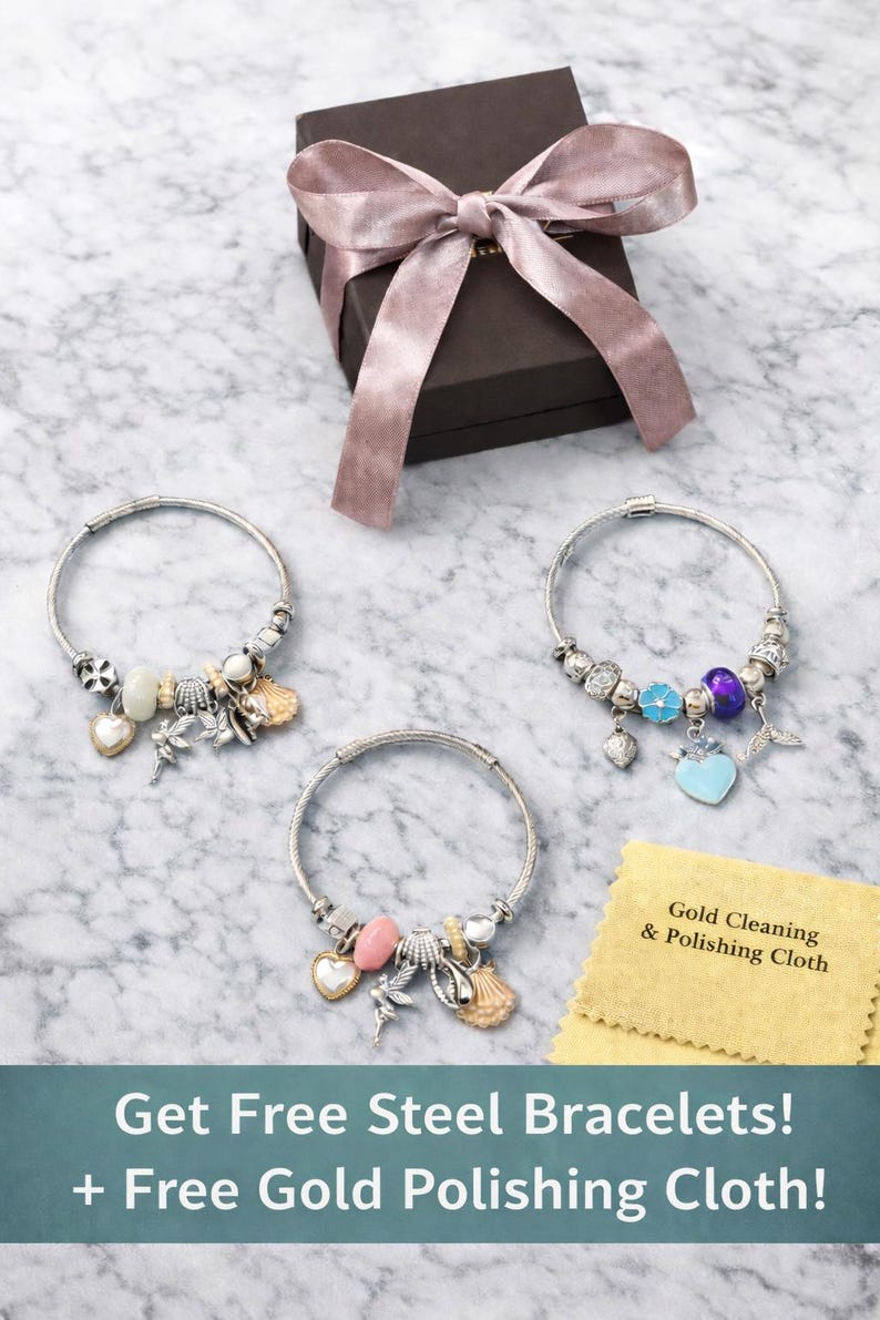 Pode incluir: Tr&ecirc;s pulseiras de berloques prateadas com v&aacute;rias contas e pingentes, incluindo conchas, cora&ccedil;&otilde;es e uma fada. Uma caixa de presente marrom escura com uma fita malva e um pano amarelo com a etiqueta Gold Cleaning & Polishing Cloth.
