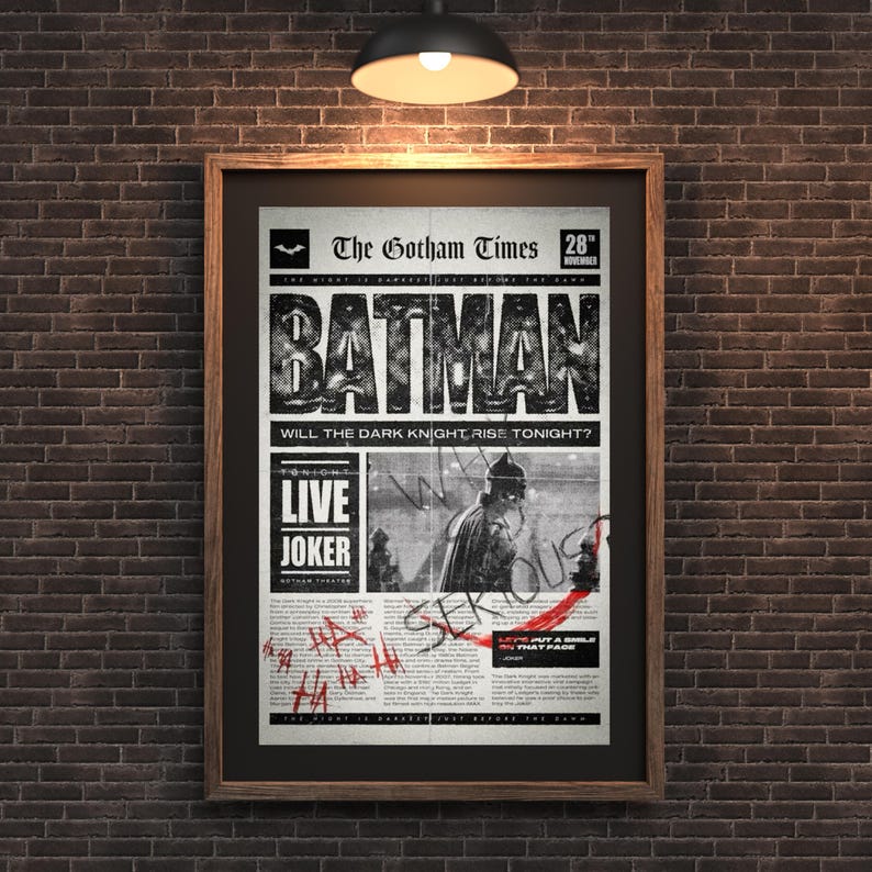 Może przedstawiać: Oprawiony plakat z motywem gazety w stylu vintage z nagł&oacute;wkiem "BATMAN". Plakat zawiera tekst "The Gotham Times", "LIVE JOKER" i "WILL THE DARK KNIGHT RISE TONIGHT?" Czerwony tekst w stylu graffiti nakłada się na obraz, zamontowany na ceglanej ścianie.