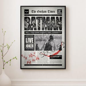 Może przedstawiać: Oprawiony czarno-biały wydruk gazety zatytułowanej "The Gotham Times" z nagł&oacute;wkiem "BATMAN". Wydruk zawiera tekst "WILL THE DARK KNIGHT RISE TONIGHT?" i "LIVE JOKER". Widoczny jest r&oacute;wnież czerwony tekst w stylu graffiti i znak zapytania.