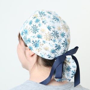 May include: A white scrub cap with a blue and gold snowflake pattern and a navy blue ribbon tie.
