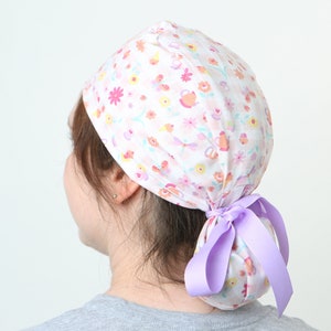 May include: A white scrub hat with a floral print and a purple ribbon tied at the back.
