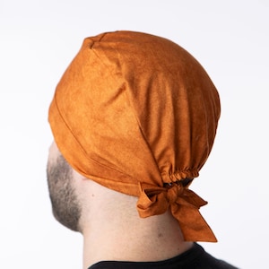 May include: A brown scrub hat with a tie at the back. The hat is made of a soft, comfortable fabric.