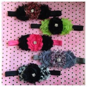 May include: Five fabric headbands with a large flower accent. The flowers are made of black, green, pink, gray, and black fabric. Each flower has a rhinestone in the center.