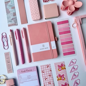 May include: A collection of pink stationery items including a pocket book, pens, bookmarks, sticky notes, paper clips, a hair clip, and a pencil case. The items feature various patterns like cherries and croissants, with text including "BOOK WORM", "POCKET BOOK", and "Book Review".