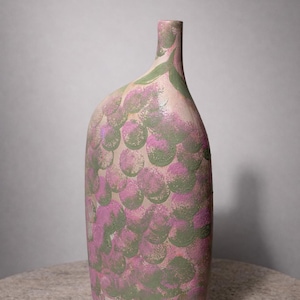Könnte beinhalten: Eine dekorative, handbemalte Keramikvase. Die Vase hat eine einzigartige, längliche Form und ist mit einem Muster aus sich überlappenden Kreisen in Rosa- und Grüntönen verziert. Die Vase steht auf einer neutralen Oberfläche.