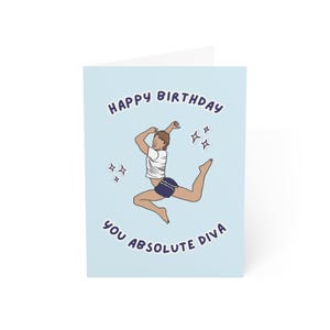 May include: A light blue birthday card with the text "Happy Birthday You Absolute Diva" in dark blue. The card features an illustration of a person in a white shirt and blue shorts doing a leap, with star accents.
