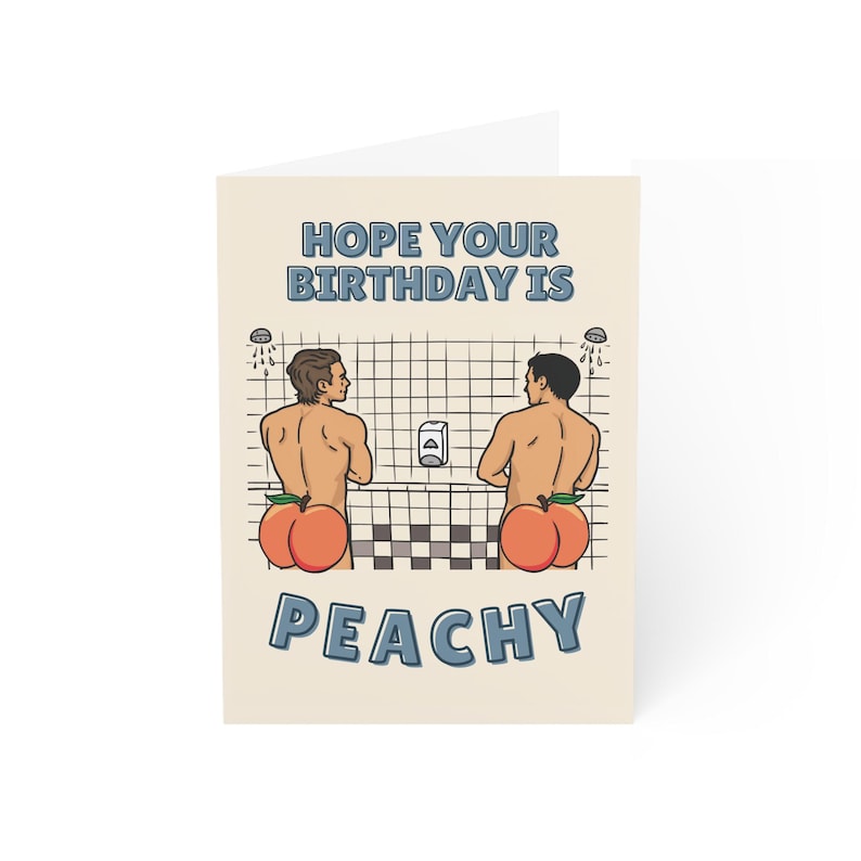 May include: A folded greeting card with the text "HOPE YOUR BIRTHDAY IS PEACHY". The card features an illustration of two men with peach-shaped bottoms in a shower setting. The background is a light beige color.