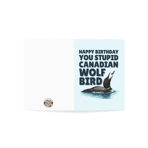 Puede incluir: Una tarjeta de cumplea&ntilde;os humor&iacute;stica con una ilustraci&oacute;n de dibujos animados de un somorgujo en el agua. La tarjeta presenta el texto "Happy Birthday You Stupid Canadian Wolf Bird" en azul oscuro. El somorgujo es blanco y negro.
