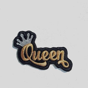 May include: A black and gold embroidered patch with the word "Queen" and a silver crown.