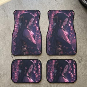 May include: A set of four rectangular car floor mats featuring a printed illustration of a person with long dark hair, wearing traditional attire, set against a background of pink cherry blossoms and dark purple tones with black trim edges.