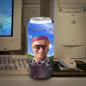 Könnte beinhalten: Ein Getränkedosenkühler mit einer lächelnden Person mit Regenbogenhaar und Sonnenbrille, vor einem blauen Himmel. Der Text "not Micro or soft" ist auf dem Kühler aufgedruckt. Der Kühler steht auf einem Schreibtisch mit Computer und Maus.