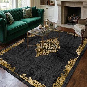 Könnte beinhalten: Ein schwarzer Teppich mit goldener, verzierter Bordüre und zentralem Design. Der rechteckige Teppich befindet sich in einem Wohnzimmer mit grünem Sofa und Glastisch. Die Abmessungen des Teppichs betragen ca. 244 x 305 cm.