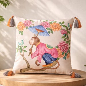 Può includere: Cuscino quadrato decorativo con un design stravagante. Presenta una scimmia che tiene un parasole blu, indossa una giacca rosa e pantaloni blu. La scimmia è appollaiata su un ramo d'albero, circondata da elementi floreali. Il cuscino ha nappe su ogni angolo.