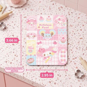 May include: A pink rectangular decorative item with a cartoon design, measuring 3.66 inches by 2.95 inches. The design includes cartoon characters, cupcakes, bows, and the text "Delicious Food". The item has a pink and white color scheme.