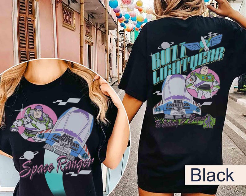 May include: A black t-shirt featuring a graphic print of Buzz Lightyear, a spaceship, and the text "Buzz Lightyear" and "Space Ranger". The design includes a circular pink background, a planet icon, and stylized lettering in shades of blue and purple.