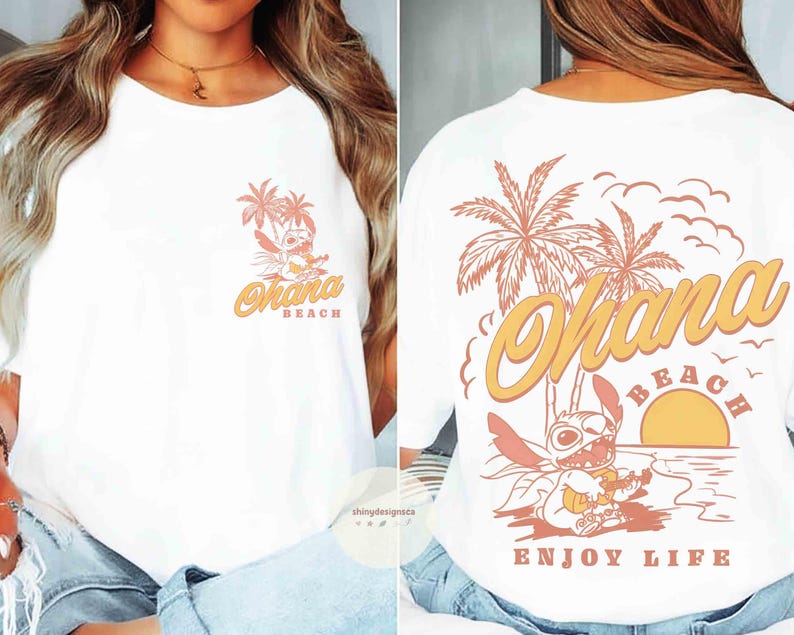 May include: White t-shirt with a front and back design. The front features a cartoon character with palm trees and the words "Ohana Beach". The back has a larger design with the same character, palm trees, a sunset, and the words "Ohana Beach Enjoy Life".