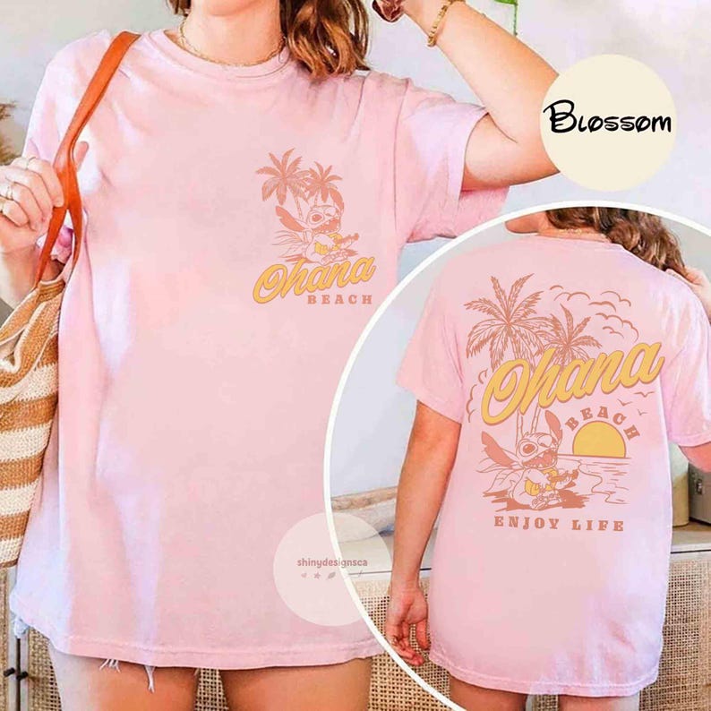 May include: Light pink t-shirt with a graphic of Stitch from Lilo & Stitch, palm trees, and the words "Ohana Beach" in yellow. The back of the shirt also features the same design with the words "Enjoy Life".