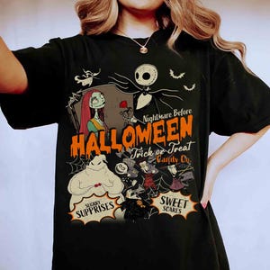May include: A black t-shirt featuring a graphic print of characters from The Nightmare Before Christmas. The design includes Jack Skellington, Sally, and Oogie Boogie with the text Nightmare Before Halloween Trick or Treat Candy Co.