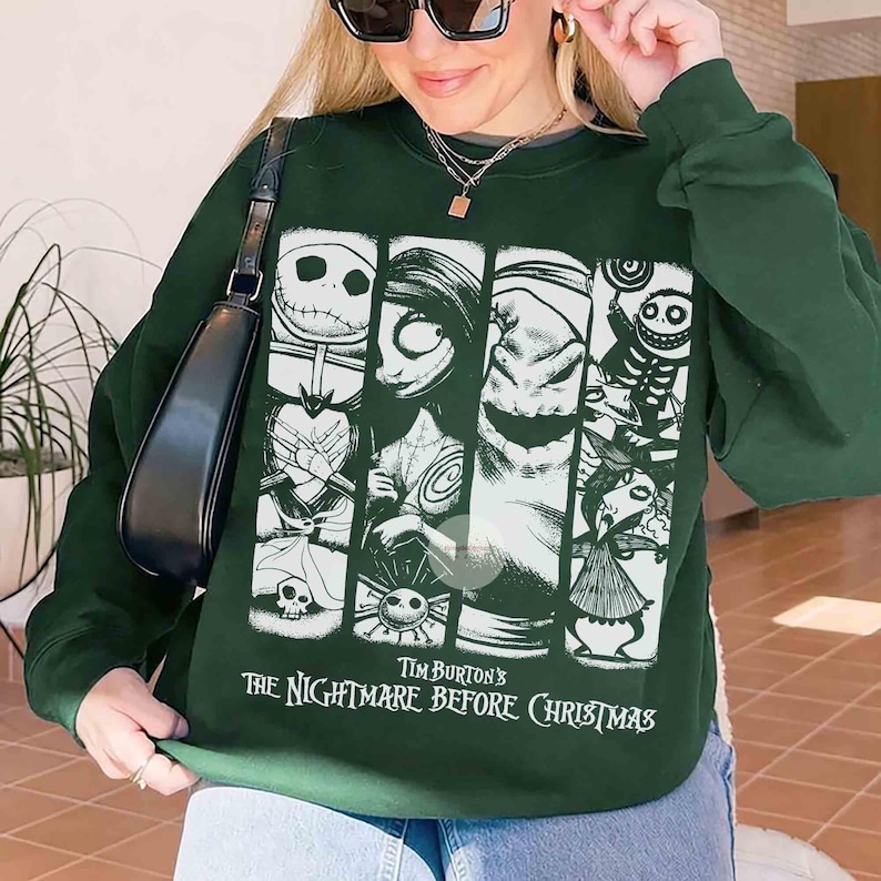 May include: Dark green sweatshirt with a graphic from Tim Burton's "The Nightmare Before Christmas." The design features characters such as Jack Skellington, Sally, and Oogie Boogie in white. The text "Tim Burton's The Nightmare Before Christmas" is printed below the graphic.