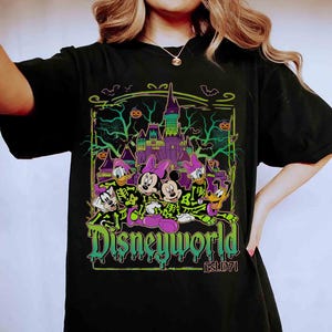 May include: Black t-shirt with a Halloween-themed Disney graphic. The design features Mickey and Minnie Mouse, Donald and Daisy Duck, and Goofy in spooky costumes, with a castle and the text "Disneyworld Est.1971".