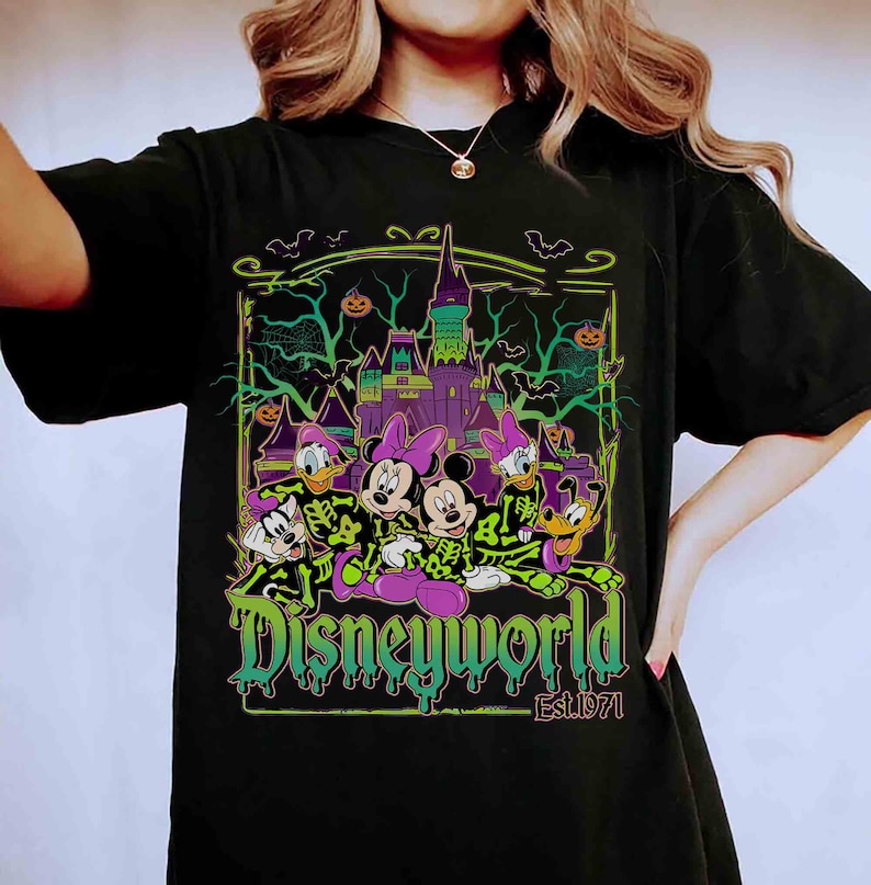 May include: Black t-shirt with a Halloween-themed Disney graphic. The design features Mickey and Minnie Mouse, Donald and Daisy Duck, and Goofy in spooky costumes, with a castle and the text "Disneyworld Est.1971".