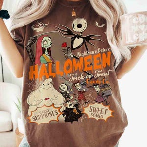 May include: A brown short-sleeve t-shirt featuring a graphic print of characters from The Nightmare Before Christmas. The design includes Jack Skellington, Sally, and Oogie Boogie with the text Nightmare Before Halloween, Trick or Treat, Candy Co.