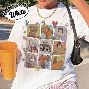 K&ouml;nnte beinhalten: Wei&szlig;es T-Shirt mit einer farbenfrohen Grafik mit Figuren aus Disneys "B&auml;renbr&uuml;der". Das Design umfasst Illustrationen von B&auml;ren und menschlichen Figuren in einem Rastermuster. Das Shirt tr&auml;gt die Aufschrift "Comfort Colors" und "White".