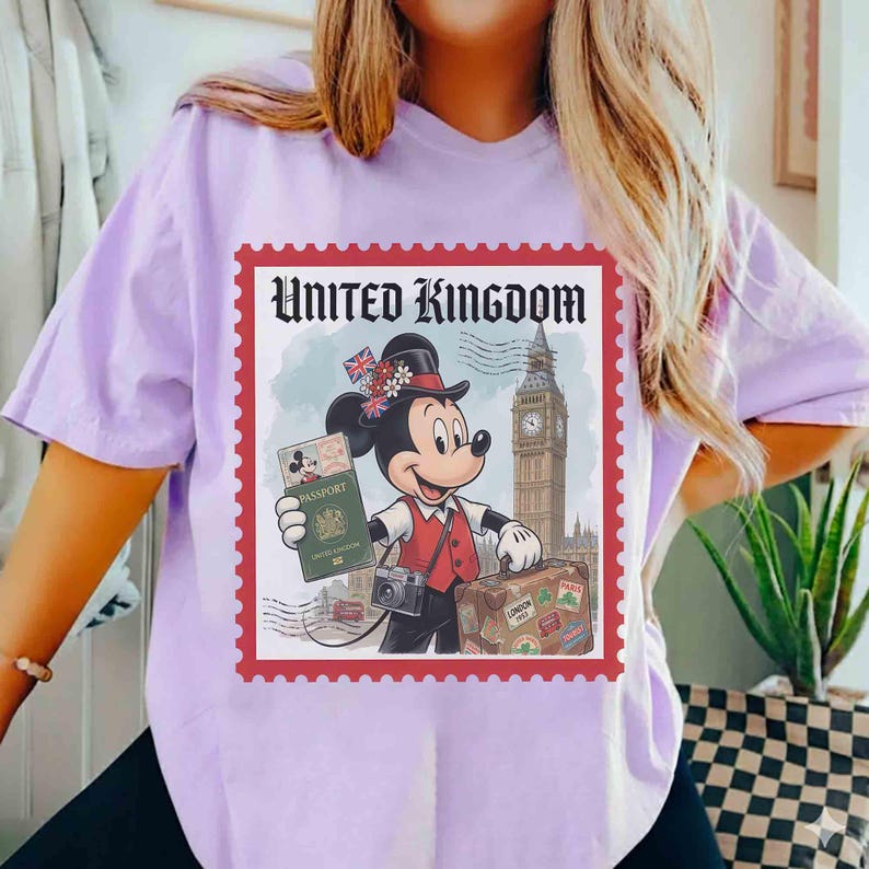May include: A lilac t-shirt with a graphic of Mickey Mouse as a traveler, holding a passport and suitcase. The graphic is framed by a red border with the words "United Kingdom" at the top. The background includes Big Ben and a London scene.