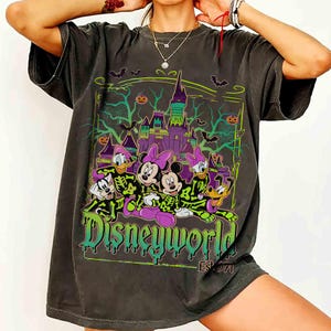 May include: Dark grey t-shirt with a Halloween Disney World graphic. The design shows Disney characters in skeleton costumes in front of a spooky castle, with the text "Disneyworld Est. 1971" in green and purple.