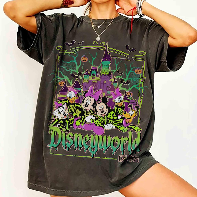 May include: Dark grey t-shirt with a Halloween Disney World graphic. The design shows Disney characters in skeleton costumes in front of a spooky castle, with the text "Disneyworld Est. 1971" in green and purple.