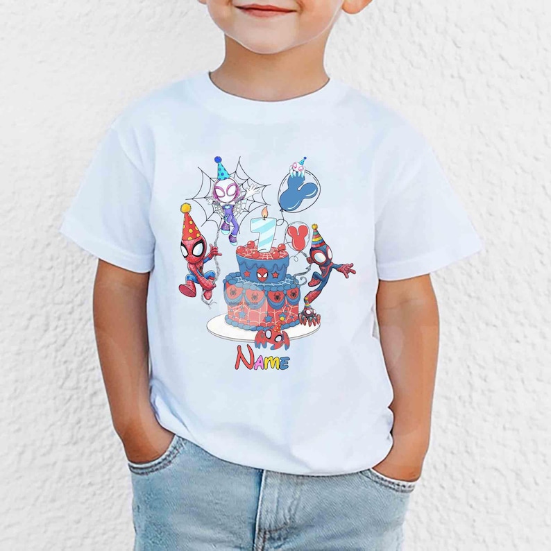 May include: White t-shirt featuring a colorful graphic of Spider-Man characters celebrating a birthday. The design includes a cake, balloons, and the word "Name". The number 7 is on the cake.