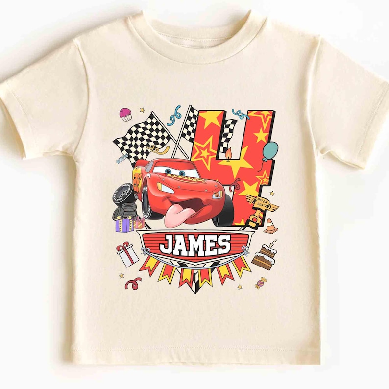 May include: Cream-colored short-sleeved t-shirt featuring a graphic of a red race car with the number 4 in red and yellow stars. The name "JAMES" is displayed on a banner below the car, with birthday-themed decorations.
