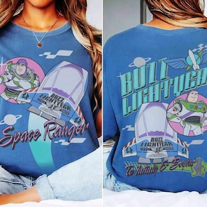 May include: A blue t-shirt featuring Buzz Lightyear graphics. The front displays Buzz Lightyear, a spaceship, and the text Space Ranger. The back shows Buzz Lightyear, a spaceship, the text Buzz Lightyear, and the phrase To Infinity & Beyond.