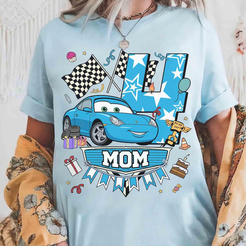 May include: Light blue t-shirt featuring a cartoon car, checkered flags, and the number 4. The word "MOM" is displayed in a banner. Additional graphics include a cupcake, gifts, and a birthday cake.