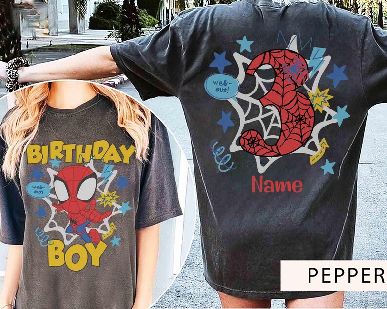 Pu&ograve; includere: Una t-shirt grigio antracite con una stampa grafica di un supereroe rosso e blu sul davanti con il testo "BIRTHDAY BOY" e "web-out!". Il retro mostra un grande numero 3 rosso con motivo a ragnatela, stelle e la scritta "Name".
