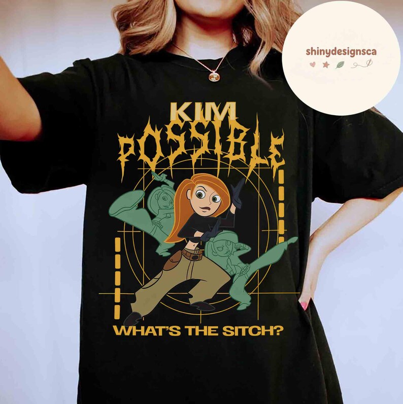 May include: Black t-shirt featuring a graphic of Kim Possible, with the text "KIM POSSIBLE" in a stylized font. The design includes Kim Possible in action, with the phrase "WHAT'S THE SITCH?" below. The shirt is a classic crew neck.