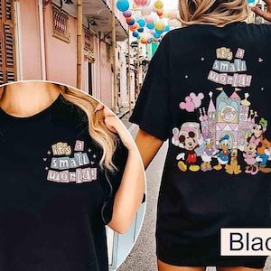 Pu&ograve; includere: T-shirt nero con la scritta "it's a small world!" sul davanti e sul retro. Il retro presenta una grafica colorata di personaggi Disney e un castello. La maglietta ha una vestibilit&agrave; ampia e oversize.