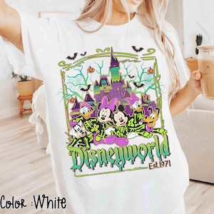 May include: White t-shirt with a Halloween design featuring Disney characters and a haunted castle. The graphic includes the words "Disneyworld" and "Est.1971" in green and black.