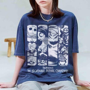 May include: Dark blue t-shirt with a graphic from Tim Burton's "The Nightmare Before Christmas." The design features characters such as Jack Skellington and Sally in a vertical panel arrangement. The text "Tim Burton's The Nightmare Before Christmas" is printed below.