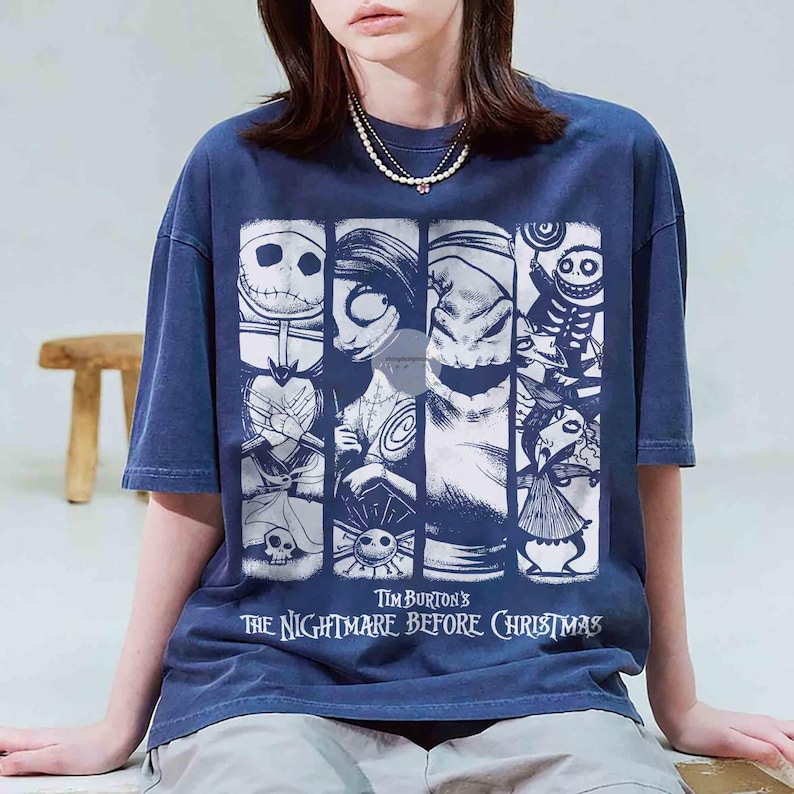 May include: Dark blue t-shirt with a graphic from Tim Burton's "The Nightmare Before Christmas." The design features characters such as Jack Skellington and Sally in a vertical panel arrangement. The text "Tim Burton's The Nightmare Before Christmas" is printed below.