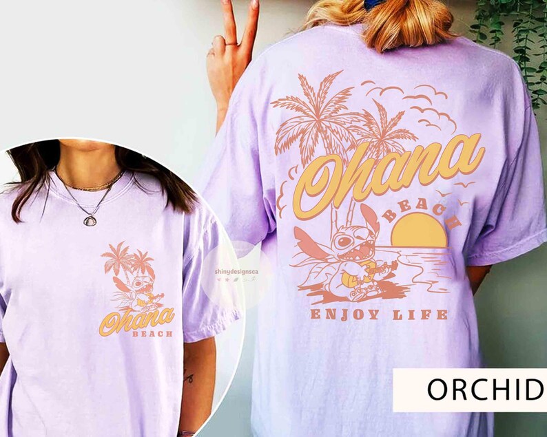 May include: Orchid-colored t-shirt featuring a graphic of a cartoon character on a beach with palm trees and the words "Ohana Beach" and "Enjoy Life". The design is repeated on the front and back of the shirt.
