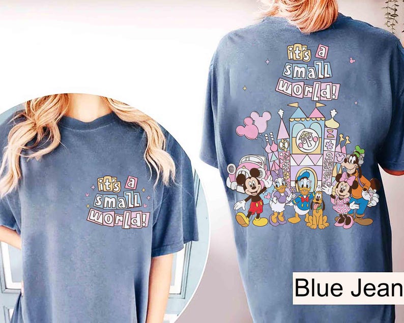 Pu&ograve; includere: T-shirt blu jeans con la scritta "it's a small world!" sul davanti e sul retro. Il retro presenta una grafica colorata di personaggi Disney e un castello.