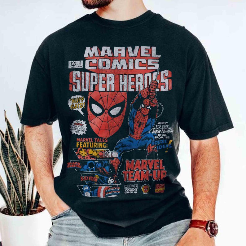 May include: A black short-sleeve t-shirt featuring a vintage-style Marvel Comics graphic. The print displays the text Marvel Comics Super Heroes, a large Spider-Man mask, and smaller illustrations of Iron Man, Black Widow, and Captain America.