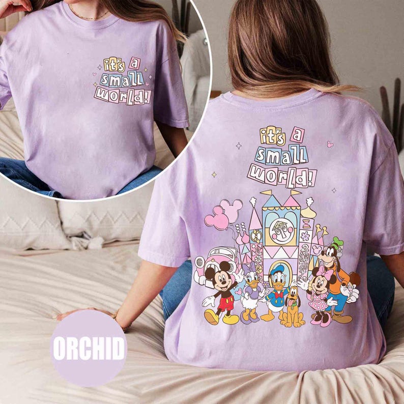 Pu&ograve; includere: T-shirt lilla orchidea con la scritta "It's a Small World!" sul davanti e sul retro. Il retro presenta una grafica colorata di personaggi Disney e un castello. La maglietta &egrave; uno stile comodo e casual.