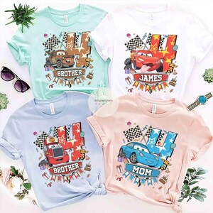 May include: Four short-sleeved t-shirts in pastel colors: mint green, white, light blue, and pink. Each shirt features a cartoon car design with the number 4 and the words "Brother", "James", and "Mom". Checkered flags and birthday cake graphics are also included.