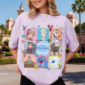 Op de afbeelding: Een lichtpaars T-shirt met een kleurrijke afbeelding van personages uit de Disney-film "Frozen". Het ontwerp bevat afbeeldingen van Anna, Elsa, Olaf, Kristoff, Sven en andere personages, met het woord "Frozen" in het midden.