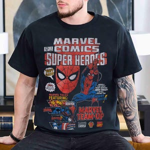May include: A black short-sleeve t-shirt featuring a vintage-style Marvel Comics graphic. The print displays Spider-Man, Iron Man, Black Widow, and Captain America with text including Marvel Comics Super Heroes and Marvel Team-Up.