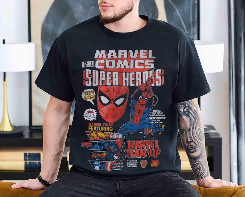 May include: A black short-sleeve t-shirt featuring a vintage-style Marvel Comics graphic. The print displays Spider-Man, Iron Man, Black Widow, and Captain America with text including Marvel Comics Super Heroes and Marvel Team-Up.